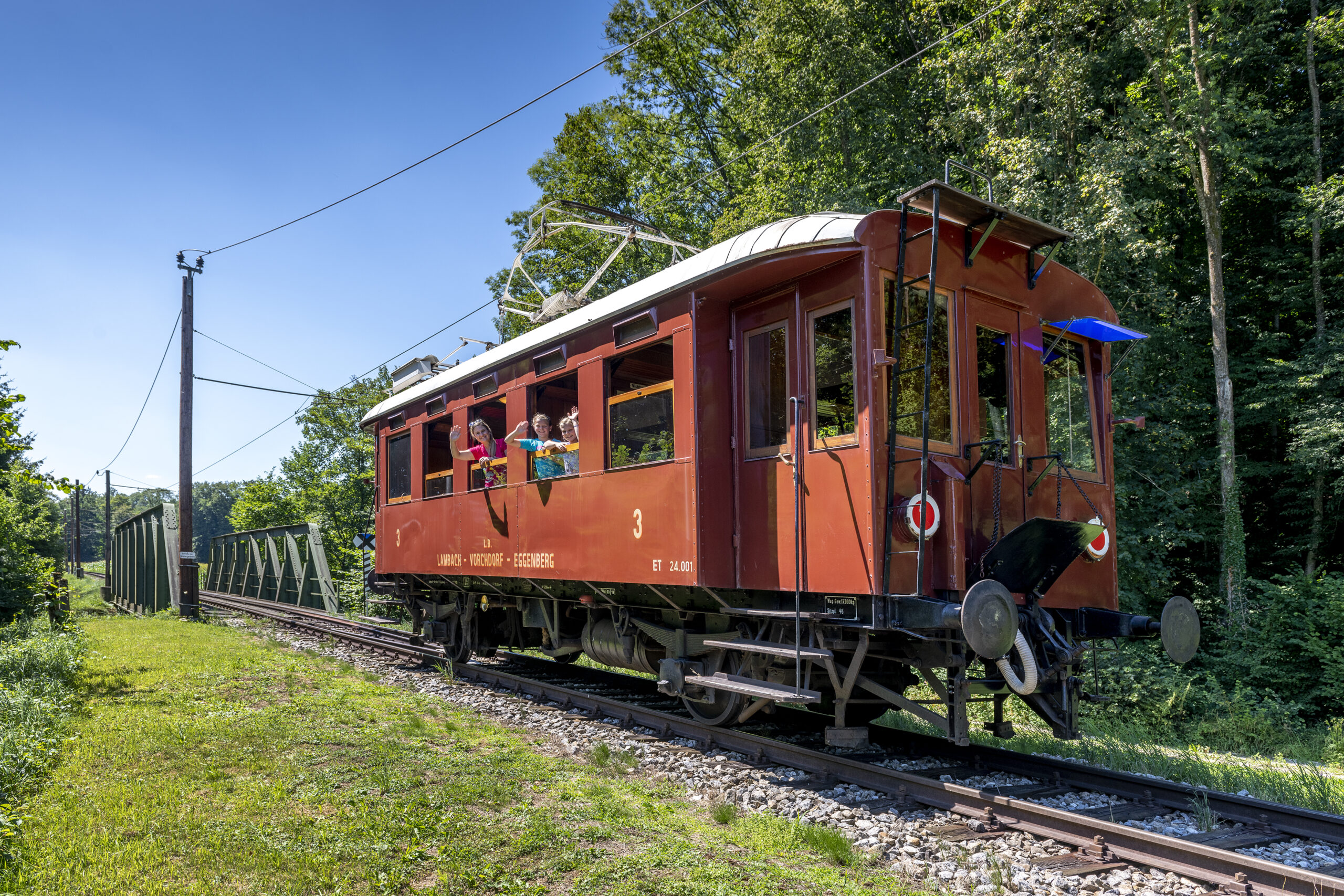 Eine Frau mit 2 Kindern sitzt in der Vorchdorferbahn und sie winken aus dem Fenster