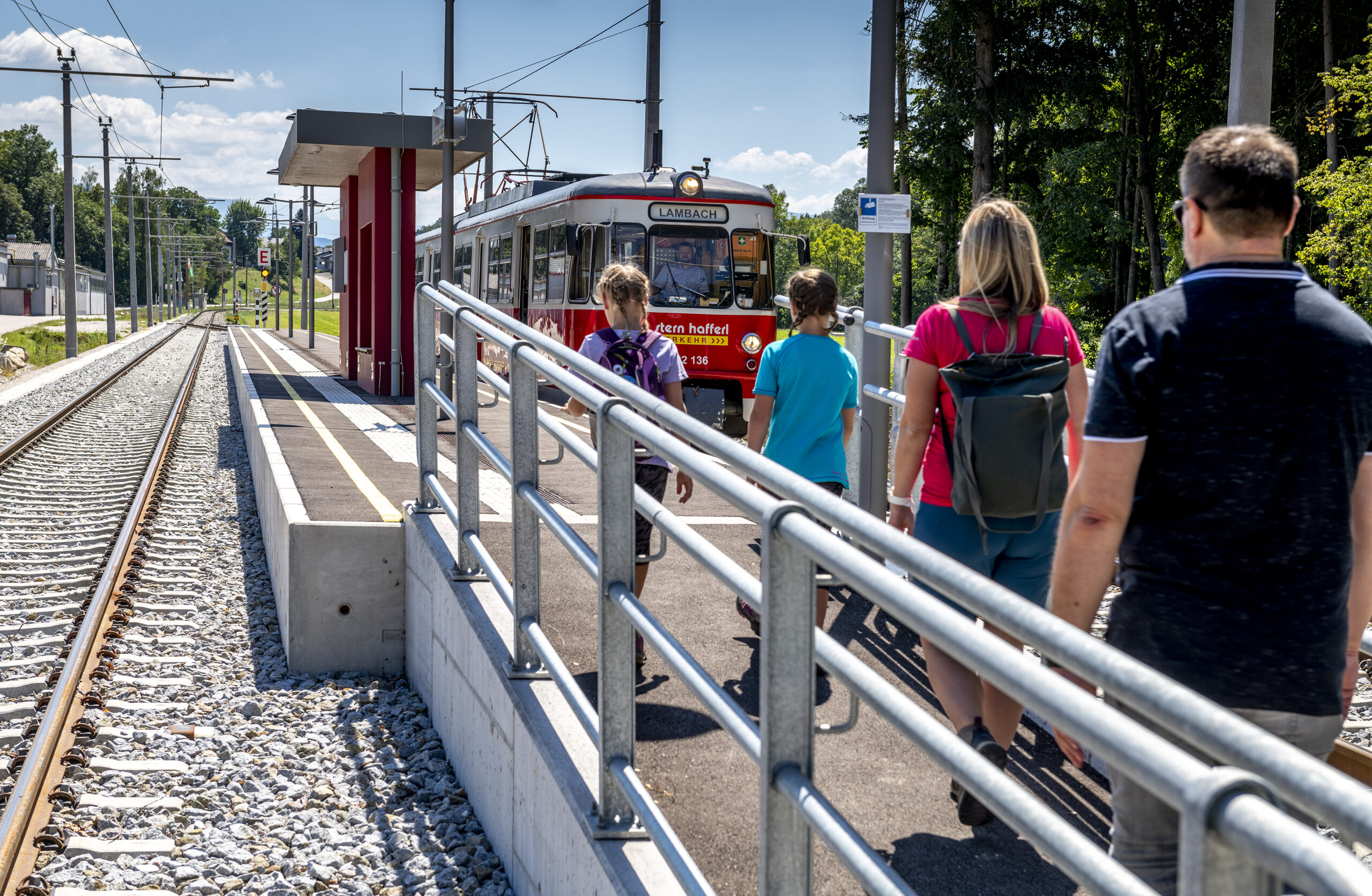 Mehrere Personen gehen zum Zug der am Bahnsteig wartet